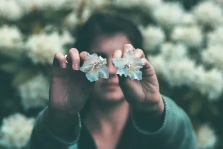 A person holding two leaves in front of their eyes.