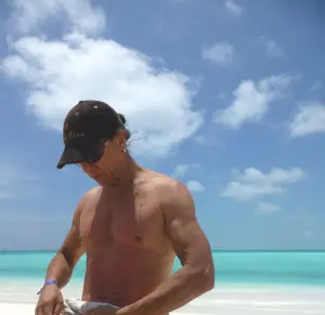 A man on the beach with his shirt off