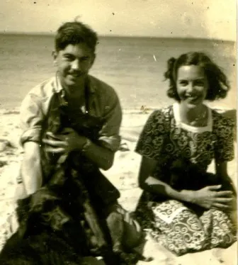 A man and woman sitting on the beach.