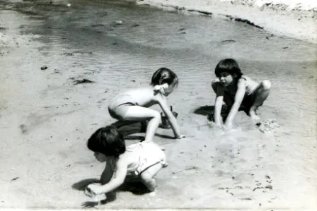 Three children playing in the sand on a beach.