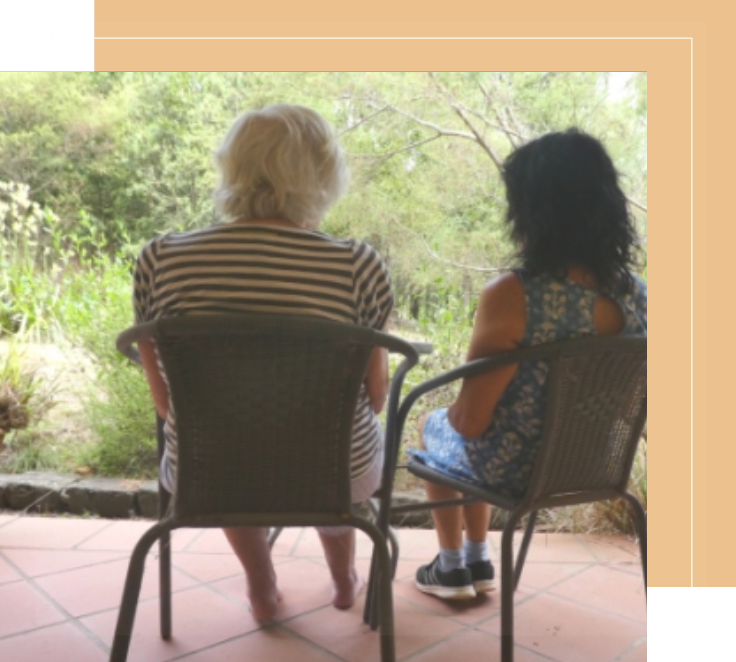 Two women sitting on lawn chairs looking out a window.