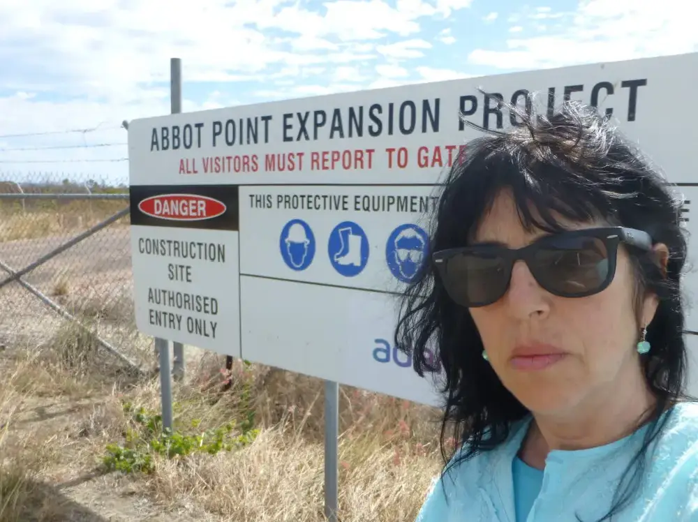 A woman standing in front of a sign.