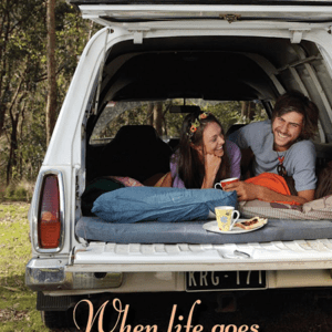 Two people sitting in the back of a truck.