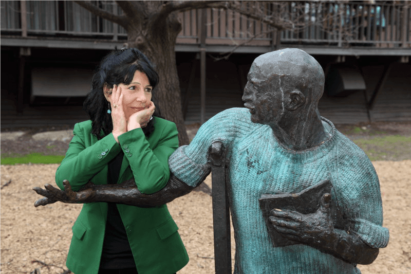 Smiling woman leaning on arm of statue