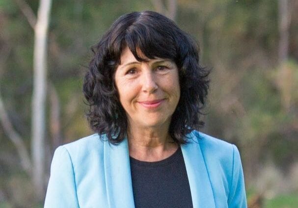 Woman in blue blazer smiling outdoors