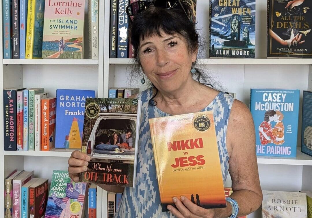 Woman holding books in front of bookshelf.
